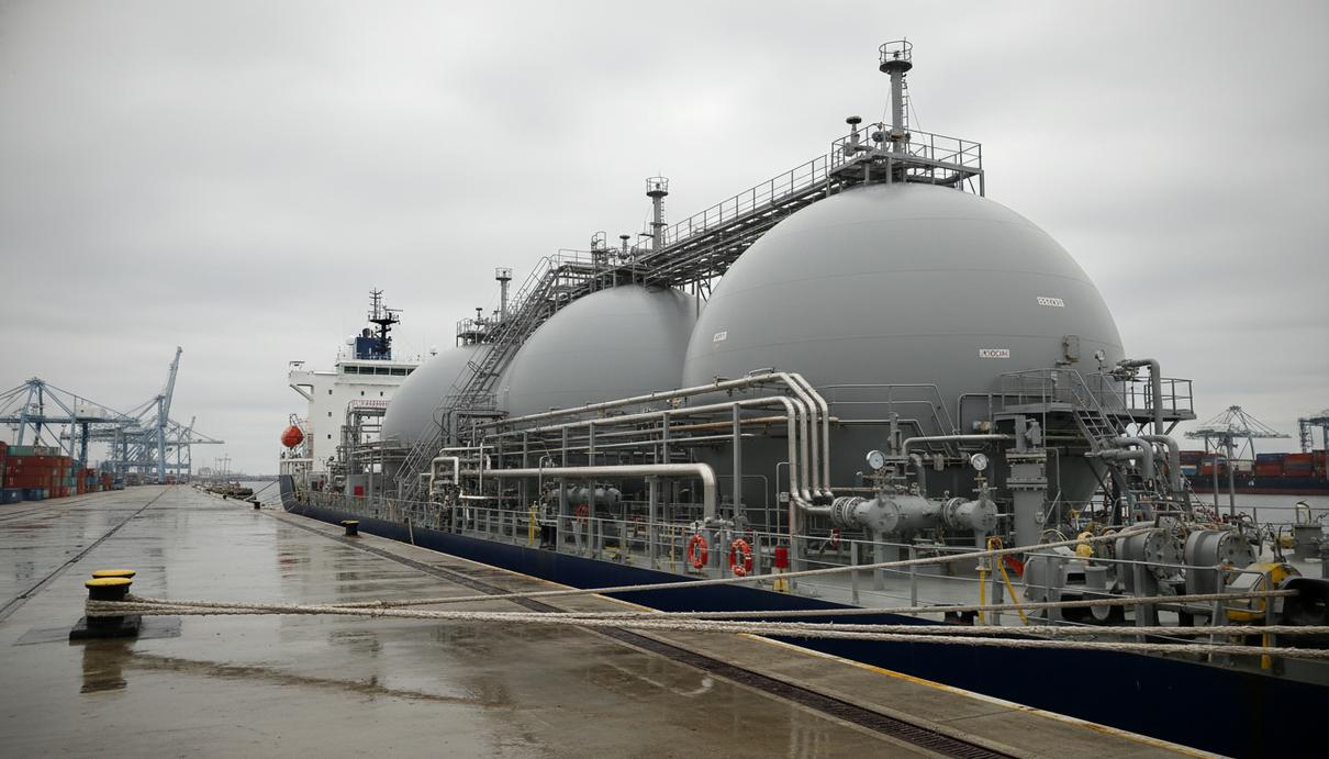 Судно-заправщик у причала промышленного терминала с газовыми резервуарами и сетью трубопроводов